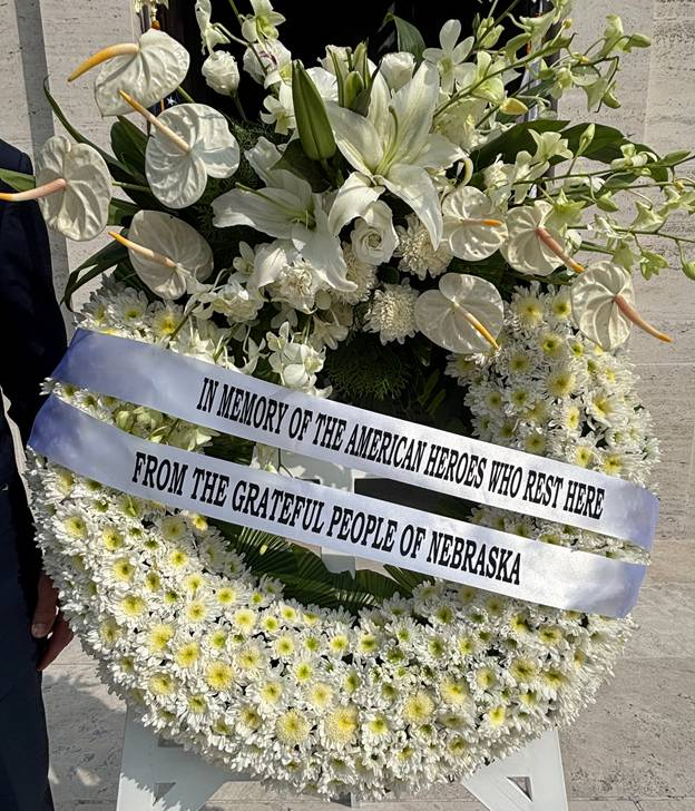 Wreath laid by Gov. Pillen at Manila American Cemetery and Memorial. The wreath is made up of a variety of white flower most of which have yellow centers. A ribbon on the wreath reads, "In memory of the American heroes who rest here from the grateful people of Nebraska".
