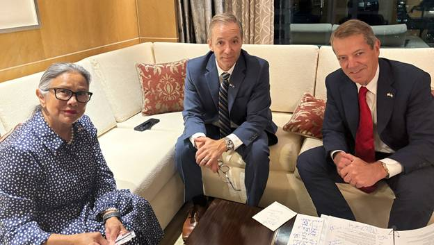 Sen. Sanders, DJ Eihusen and Gov. Pillen during interview call with Nebraska media. They are sitting on a corner couch with decorative maroon and gold pillows.
