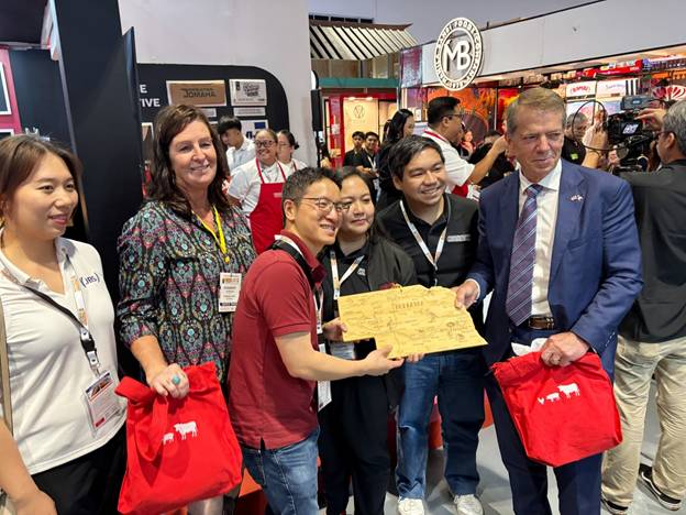 Gov. Pillen and unnamed members of the delegation hold a plaque in the shape of Nebraska while attending the World Food Expo.