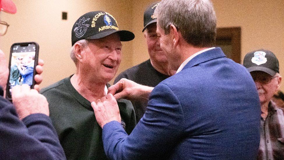 Governor Pillen presents a Vietnam War lapel pin to a Vietnam Veteran
