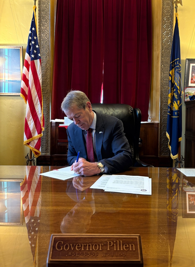 Gov. Pillen sits at his desk signing a request for Federal Disaster Declaration for Wildfire Damage