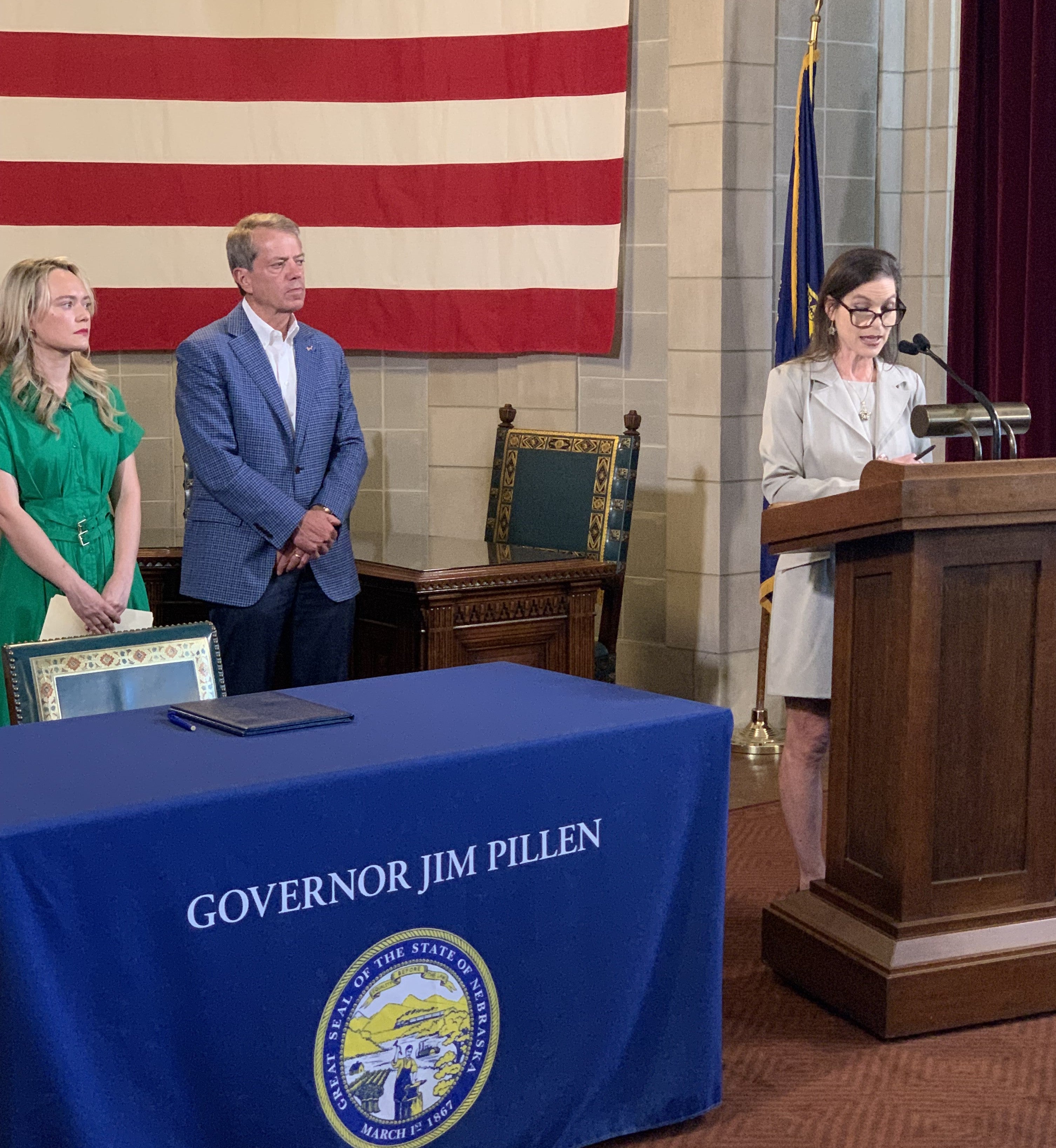 Barbara Lacina, director of the Office of Economic Assistance (OEA) addresses the audience. Others flanking her at the podium are , MiMi Greene and Governor Pillen.